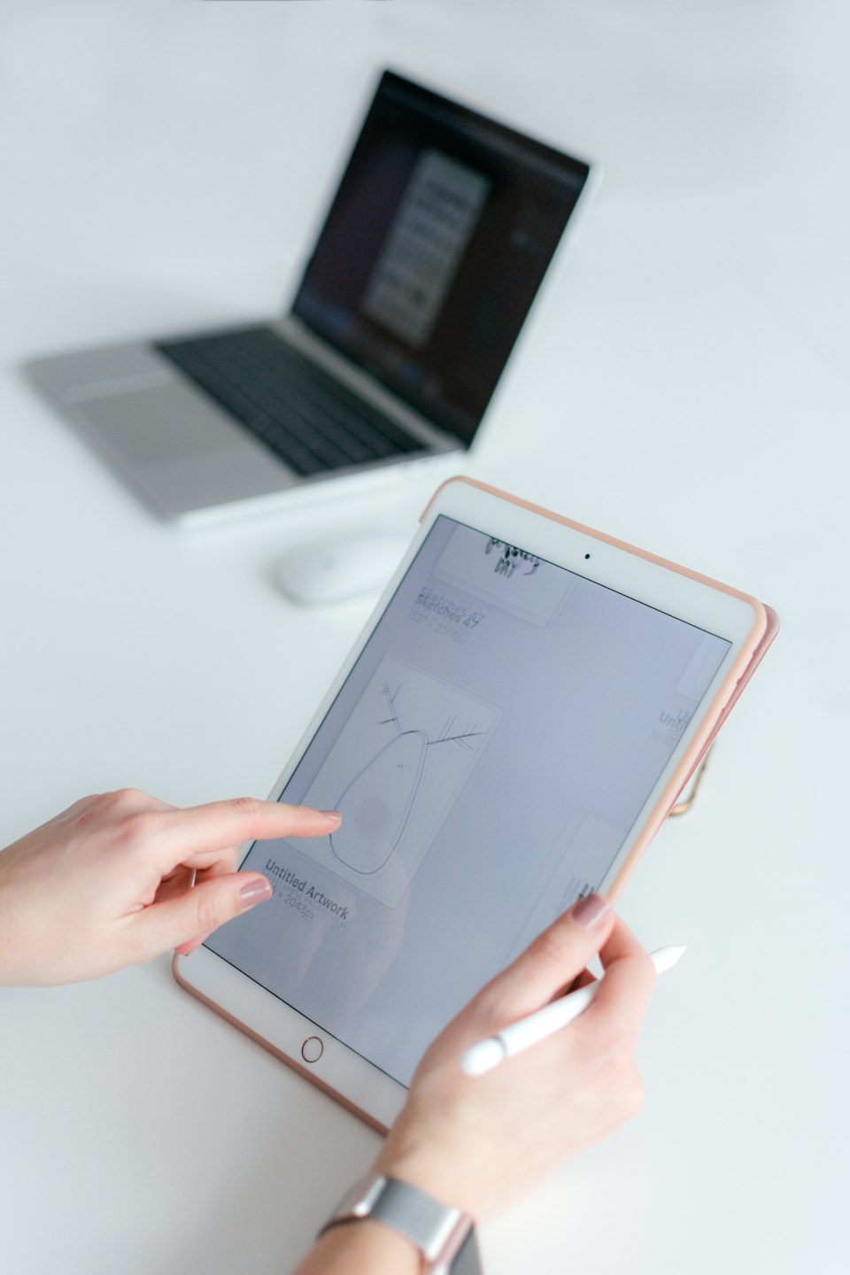 Manos usando una tablet y un lápiz óptico sobre un escritorio blanco.